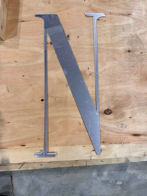 Metal letter N mounted on a wooden board backdrop