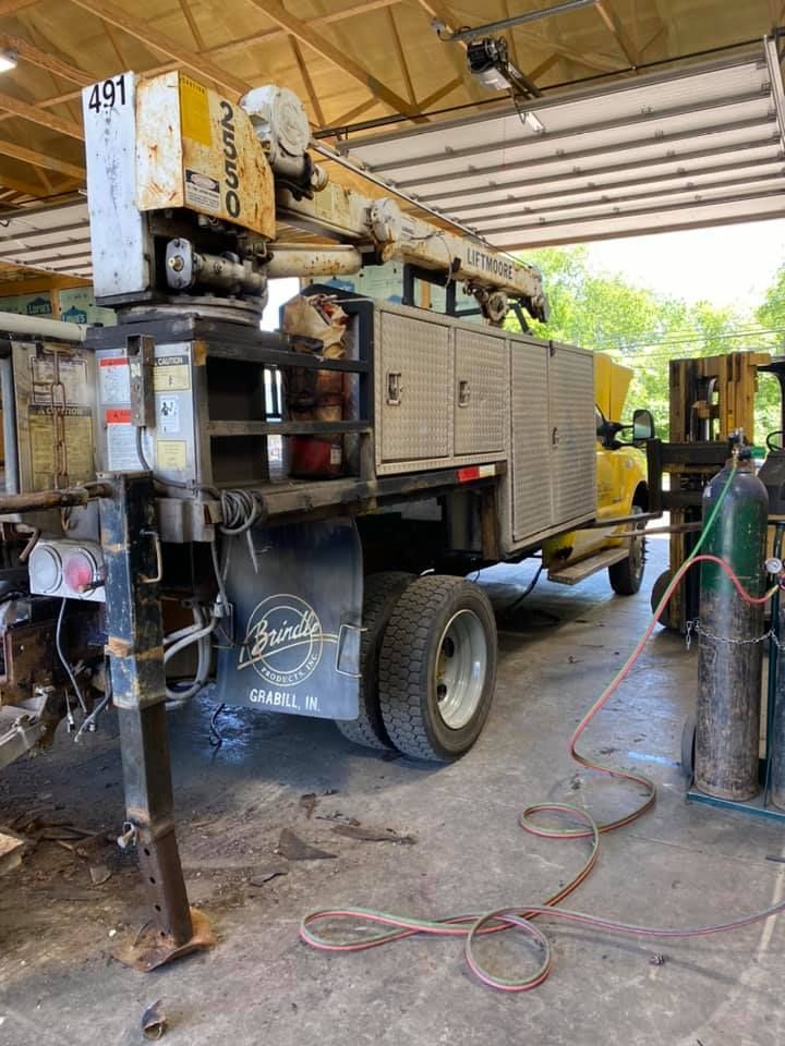 A yellow utility truck inside a garage, featuring a crane and storage compartments.