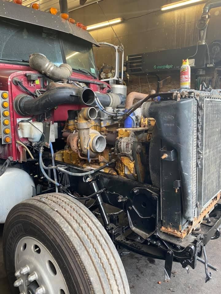 Semi-truck engine undergoing repair in a garage. The front end is open, revealing the engine.