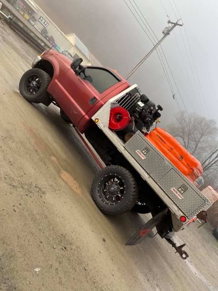 Red flatbed truck parked outdoors with black wheels and cargo.