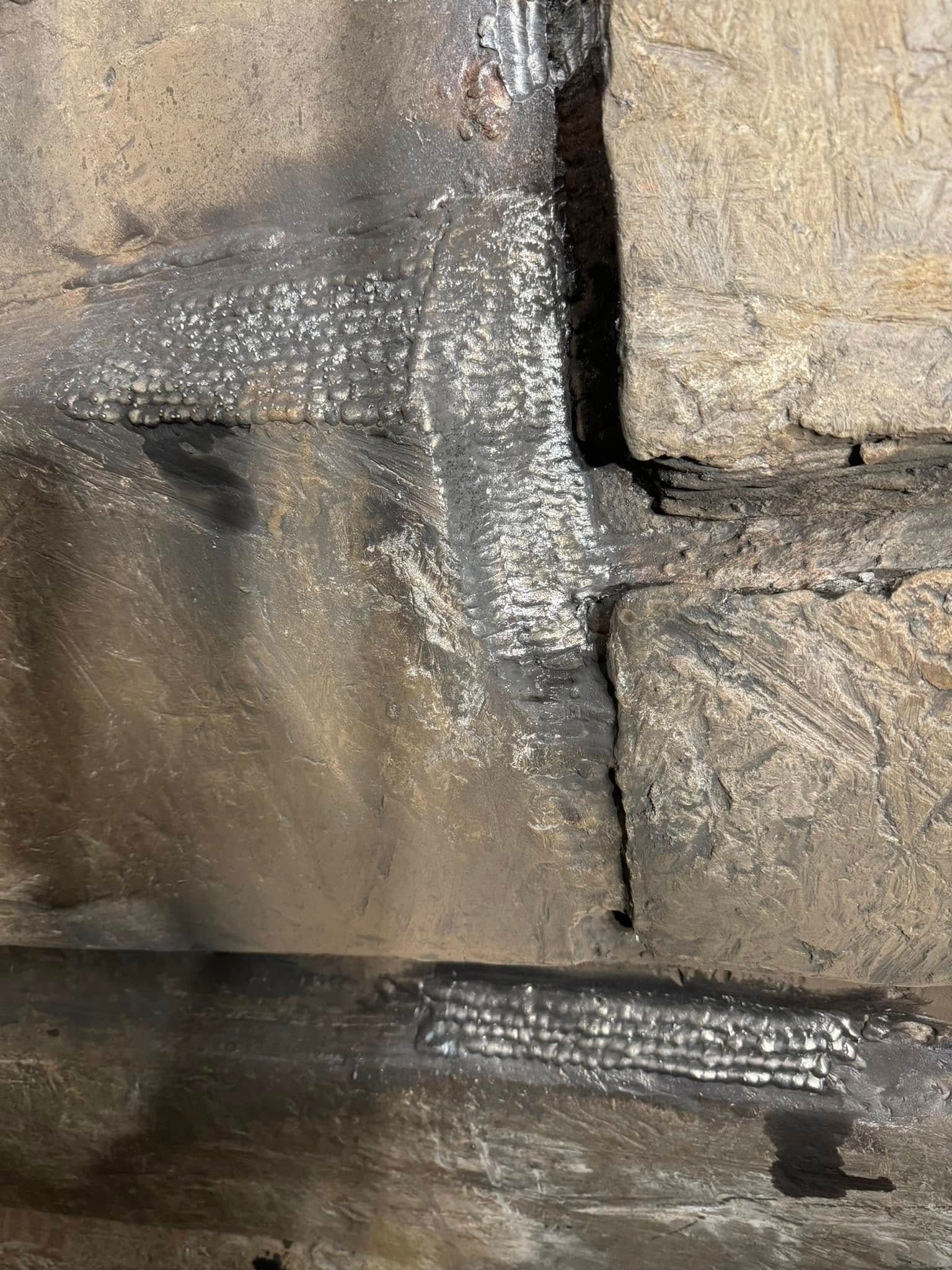 Close-up of charred stone wall with white residue, possibly from fire.