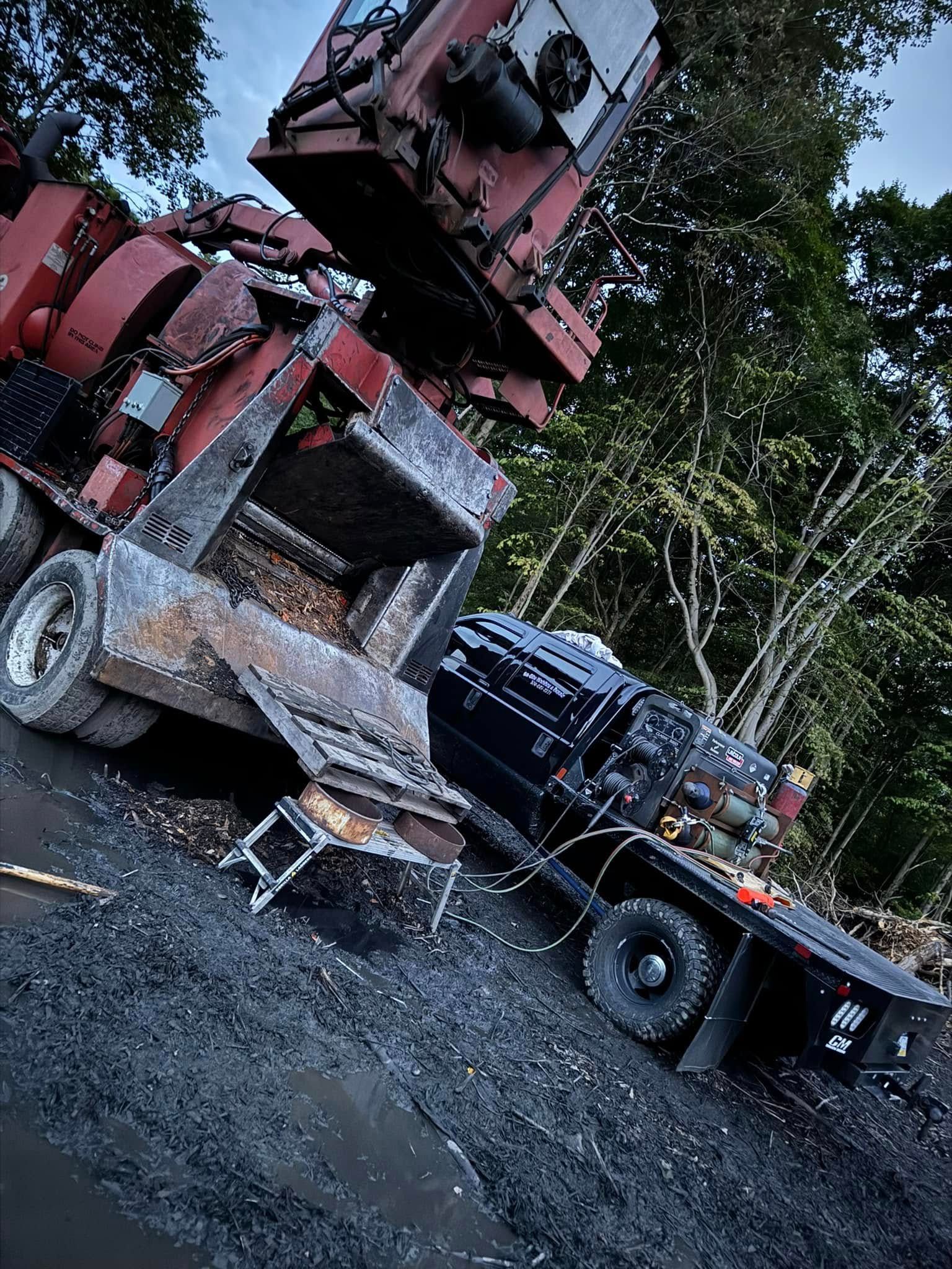 Heavy machinery on a truck, tilted on its side, near trees.