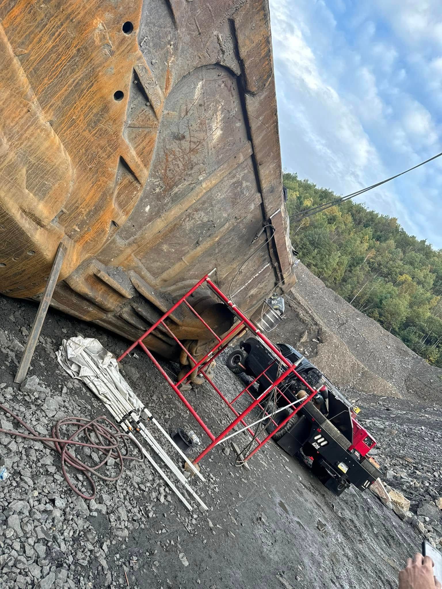 Climbers on a steep rock face with a red safety frame. Ropes, steps, and a view of trees in background.