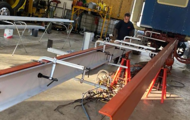 Man working on a vehicle frame; a metal structure in a workshop.