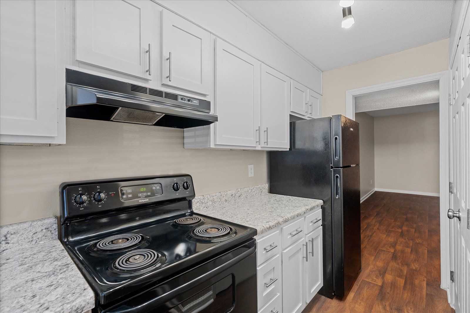 A modern kitchen featuring white cabinets, granite countertops, a black stove, and a black refrigerator.