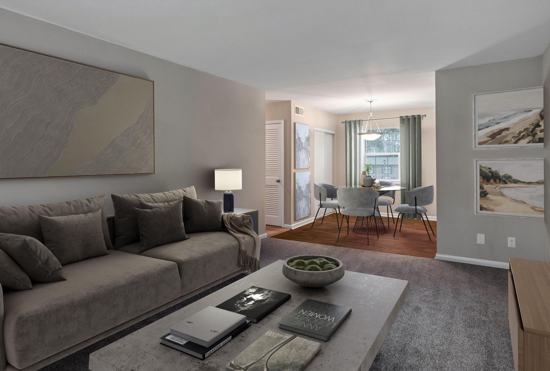 A modern living room with a large grey sofa, coffee table, and a dining area in the background with beige walls.