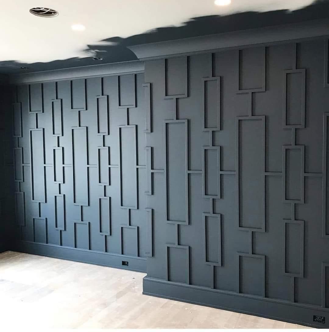 A charcoal wall featuring a geometric pattern of recessed rectangles and molding against a light wood floor.