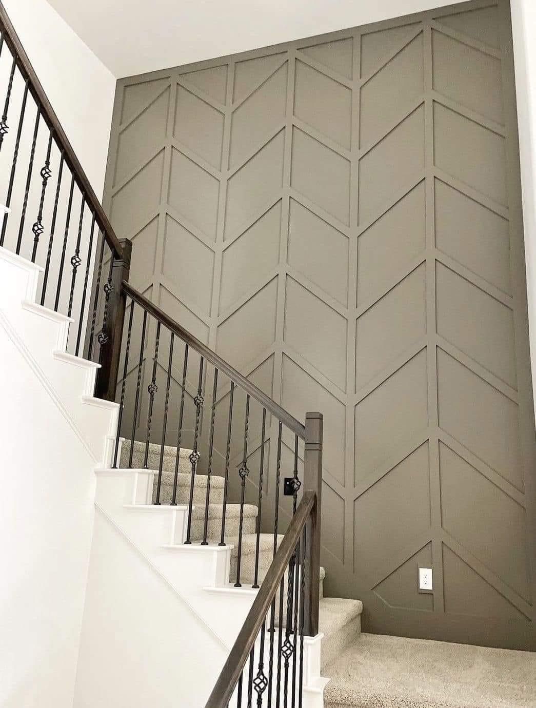 Staircase with a light brown wall featuring a geometric, chevron-patterned wood trim accent design.