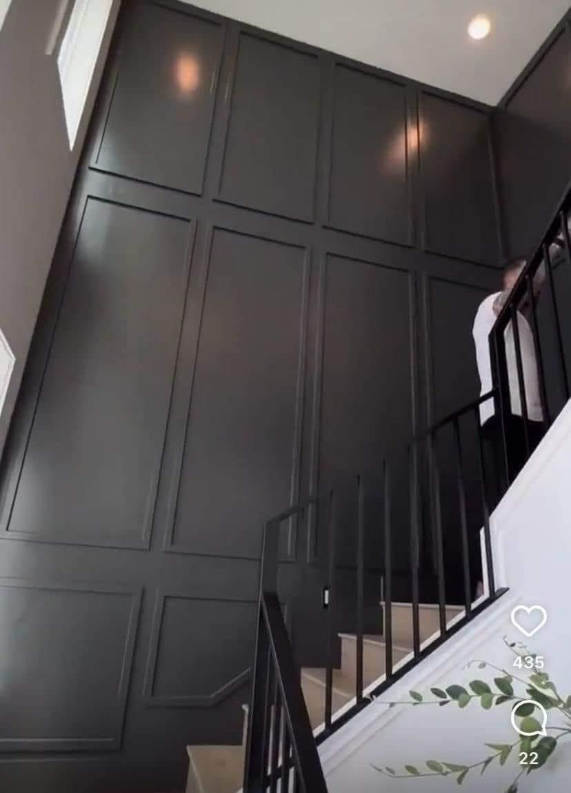 A staircase with a dark gray, paneled accent wall extending from the ground to the ceiling.