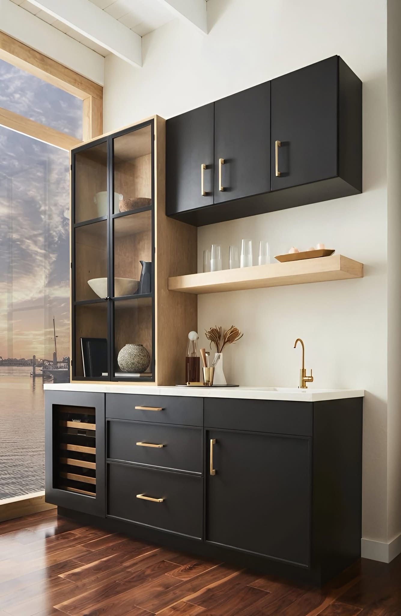 A sleek modern black wet bar with wood-toned glass cabinetry, gold hardware, a wine cooler, and a floating shelf.