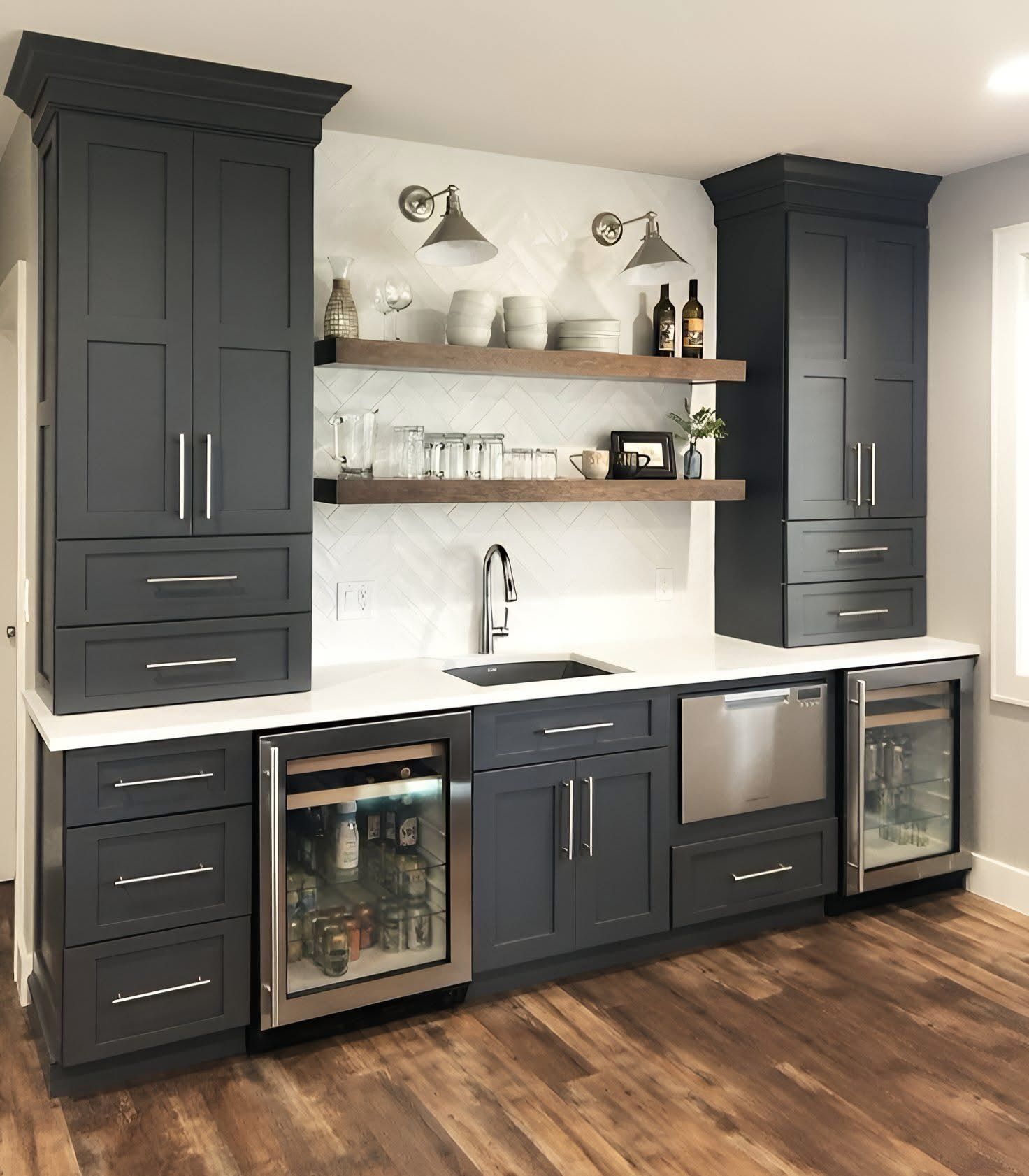 A modern bar area featuring dark charcoal cabinets, white countertops, floating wooden shelves, and stainless appliances.