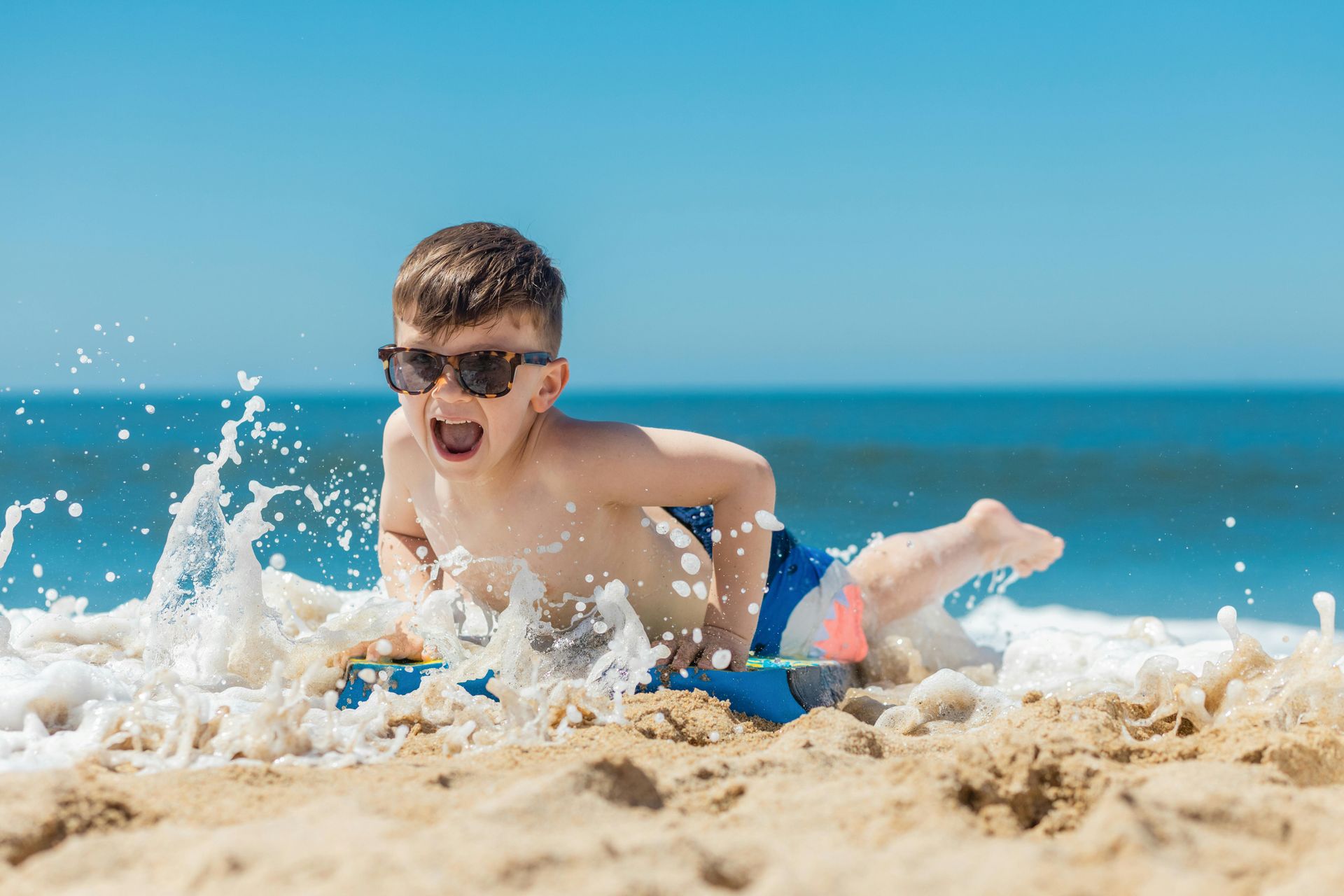 Happy boy boogie boarding in ocean Virginia Beach