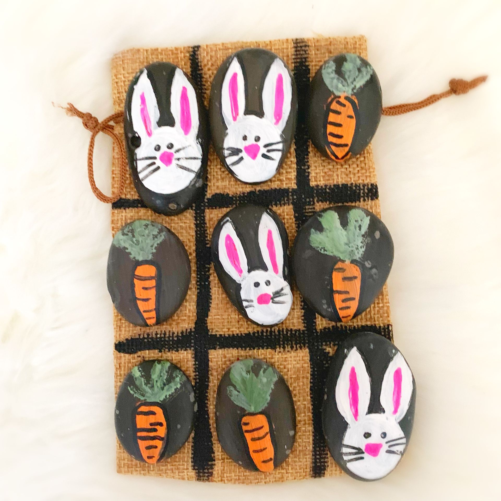 A bag of rocks with bunny faces and carrots painted on them