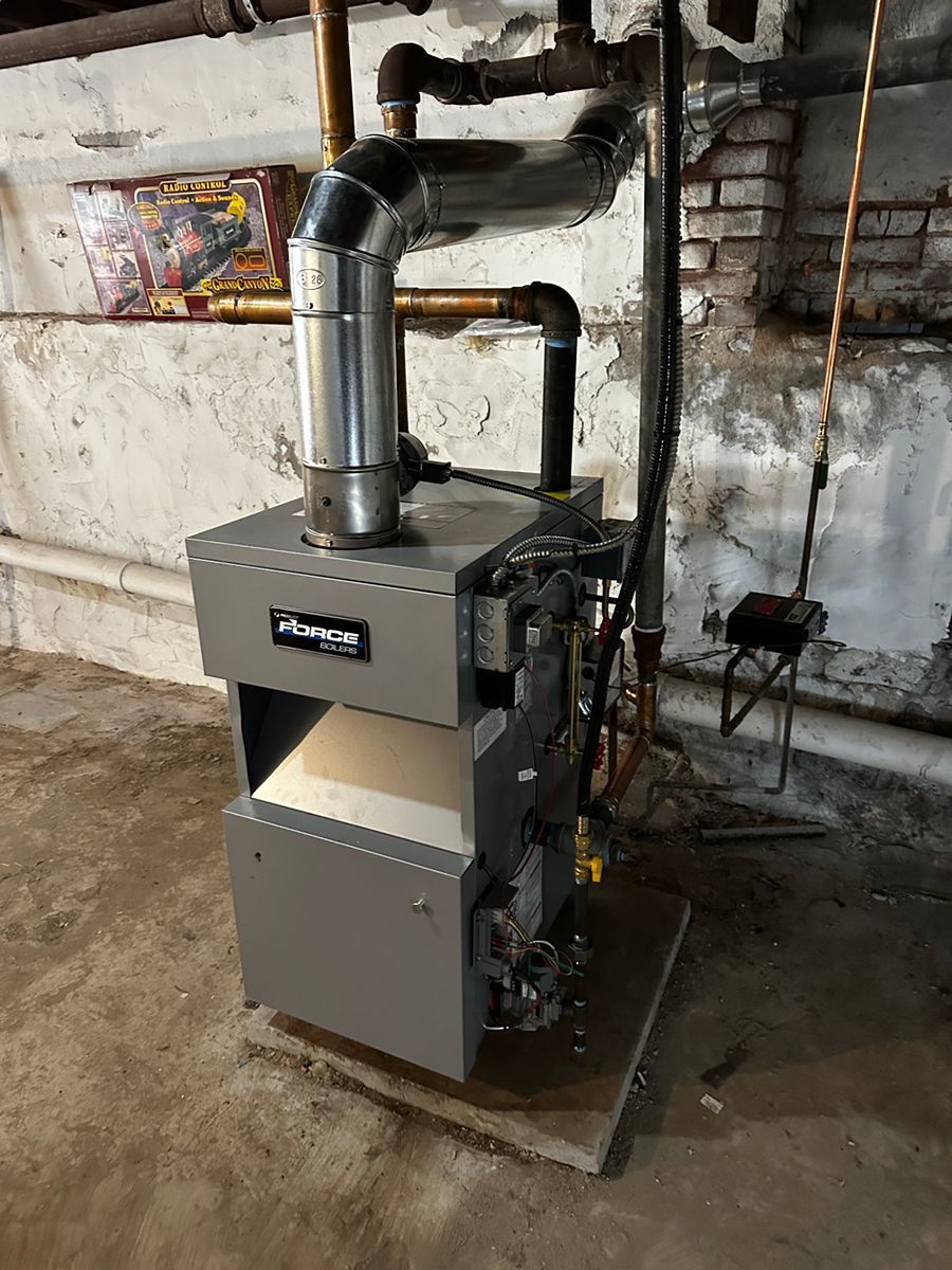 Gray industrial furnace with metal vent piping in a basement utility room