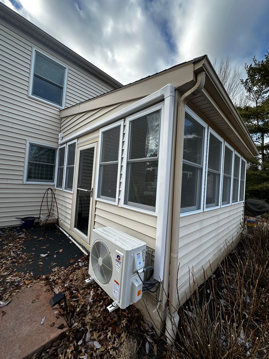 Small enclosed porch on a beige house with white trim and an outdoor AC unit attached.