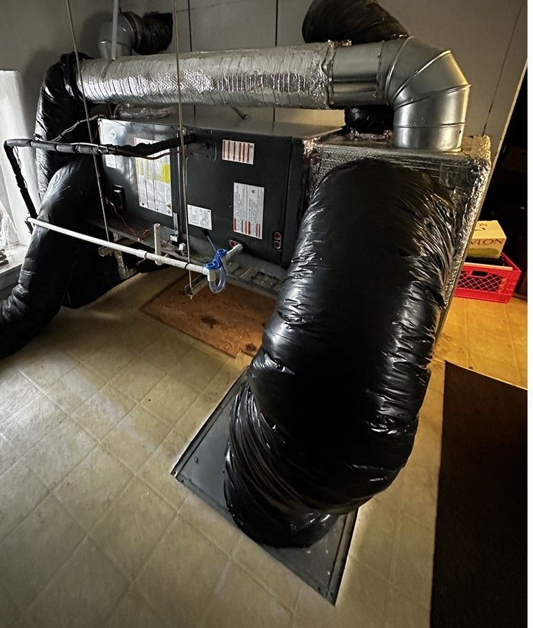 HVAC furnace with silver ductwork and black insulated flexible ducts in a utility room