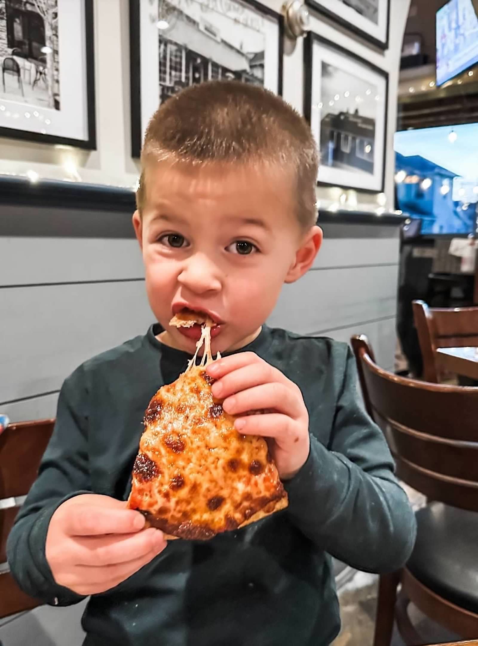 A young child eats a slice of cheese pizza in at BJ Ryan's EAST.
