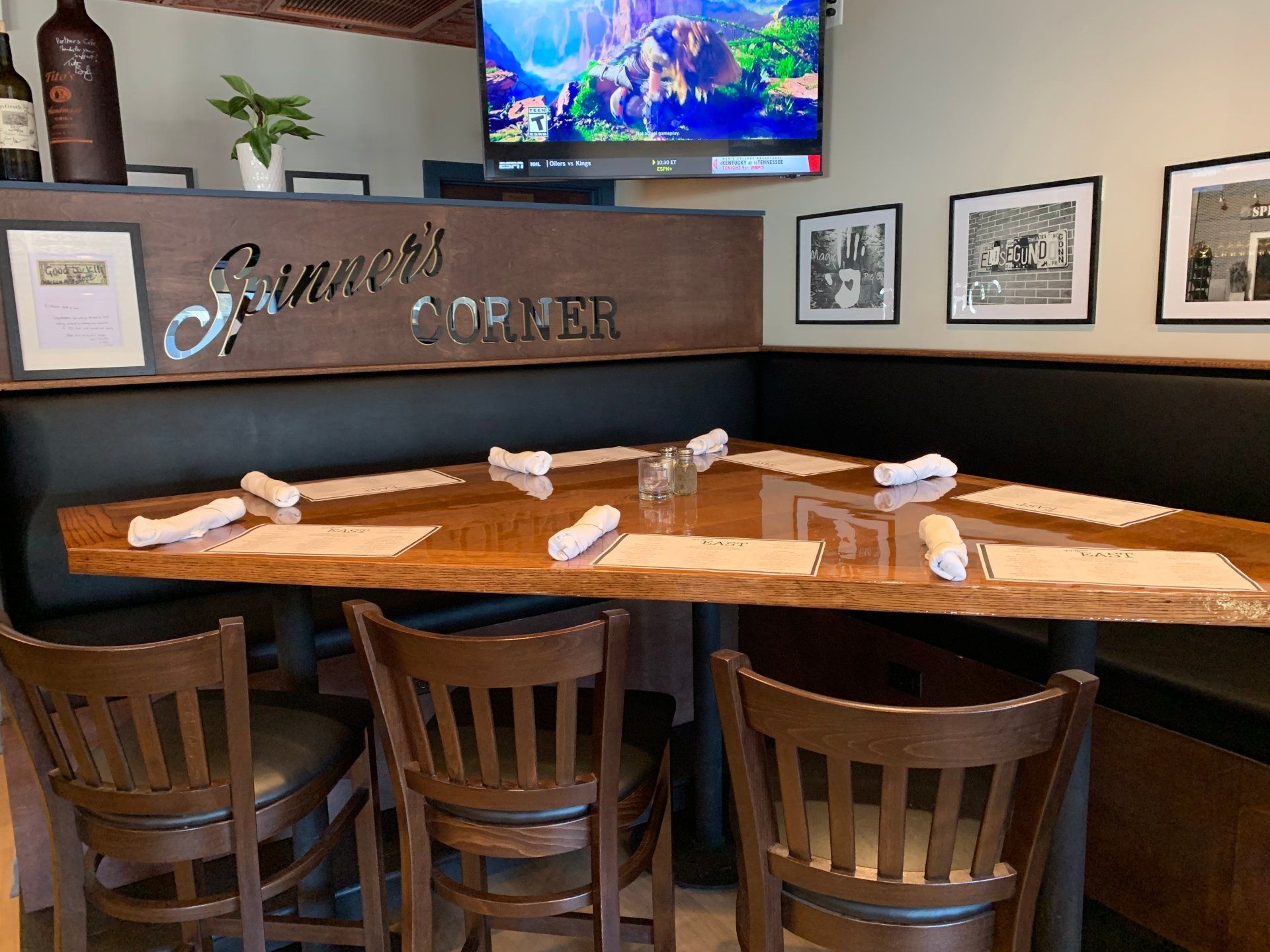 A wooden table with place settings and wooden chairs in a booth at a restaurant called 