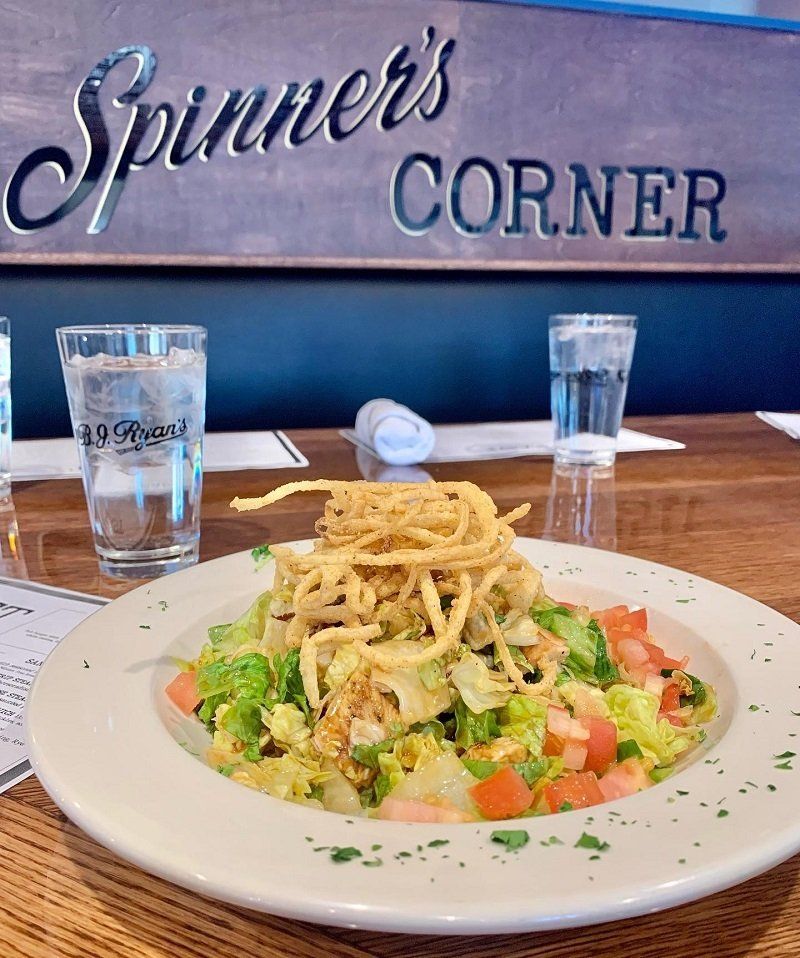 A salad topped with crispy onion strings at a restaurant table.