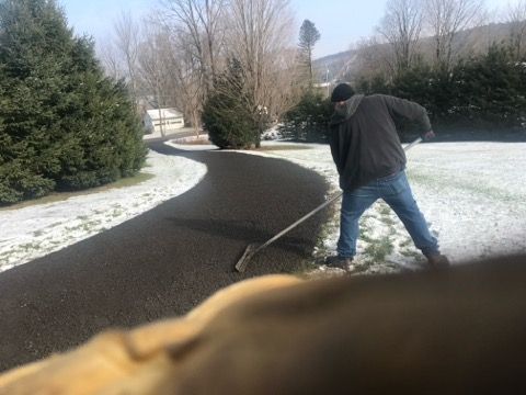Person shoveling a curved snowy driveway in a winter yard