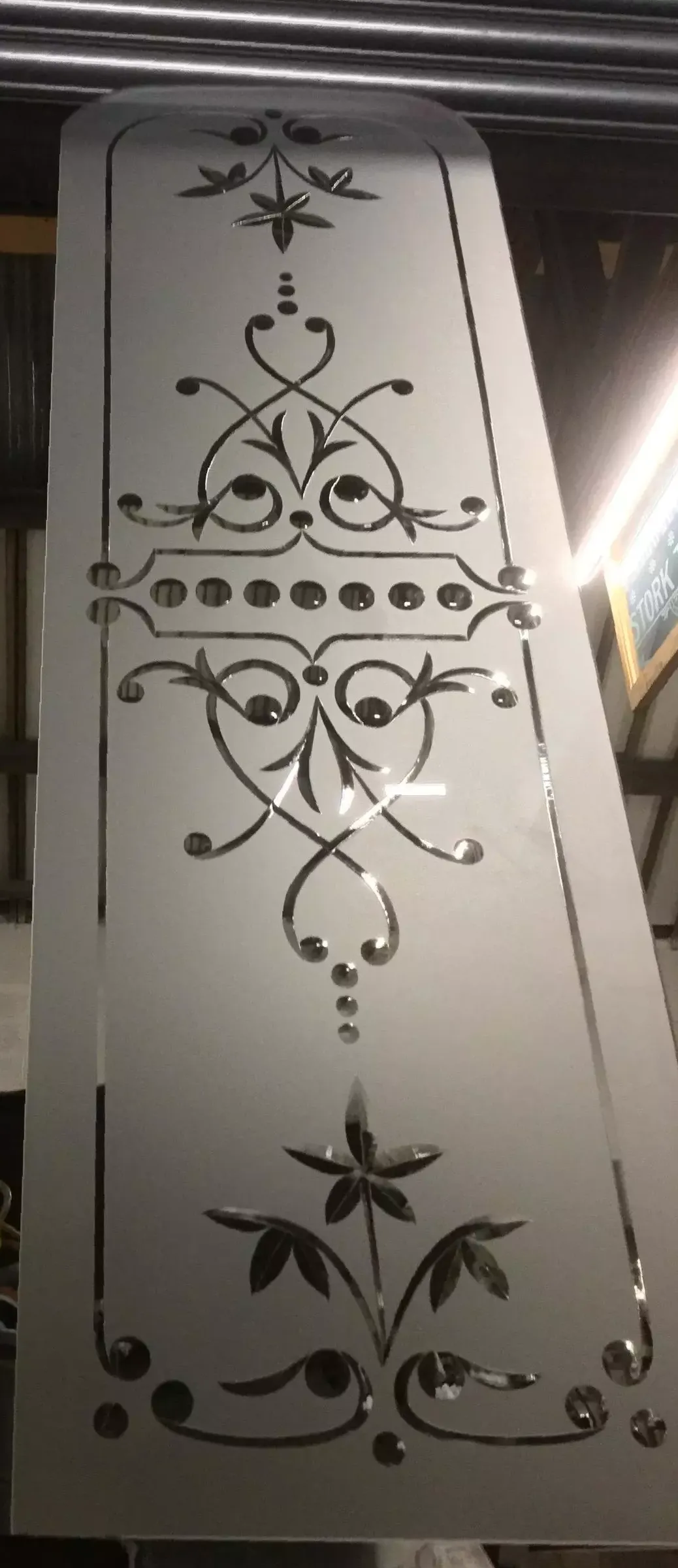 Decorative frosted glass panel with black floral scrollwork and leaf motifs on a white background