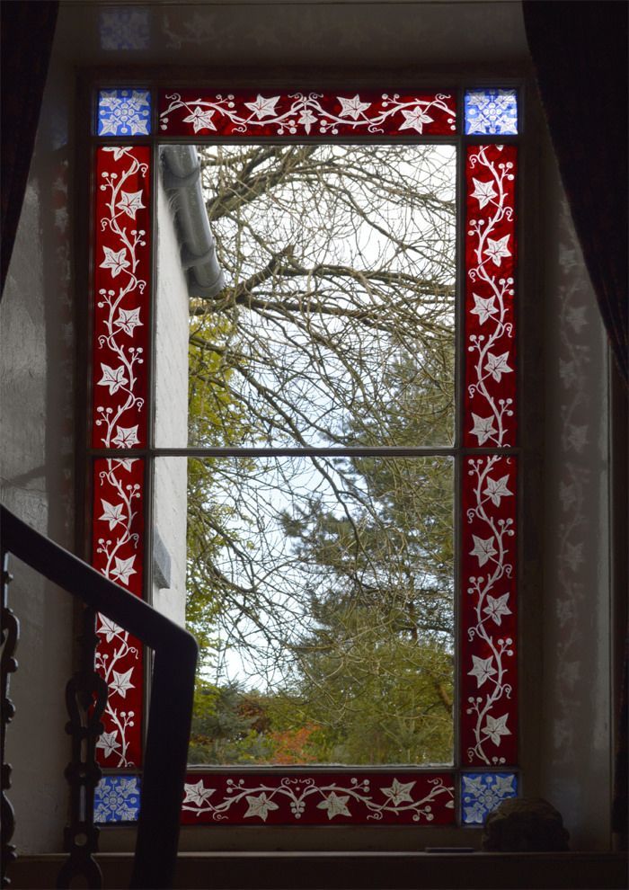 Decorative stained-glass window framing leafless tree branches and blue sky