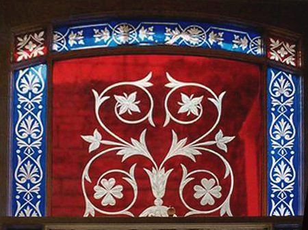 Ornate red tapestry panel with white floral designs and a blue patterned border