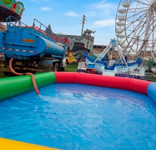 Atracción de feria colorida con una piscina azul al frente y una noria al fondo.