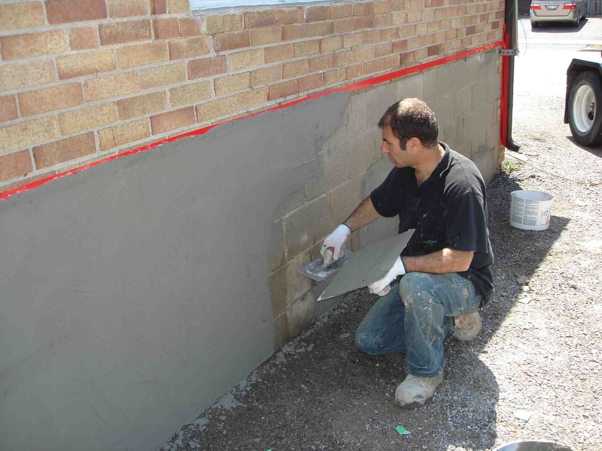 man applying a parging coat on a building's exterior