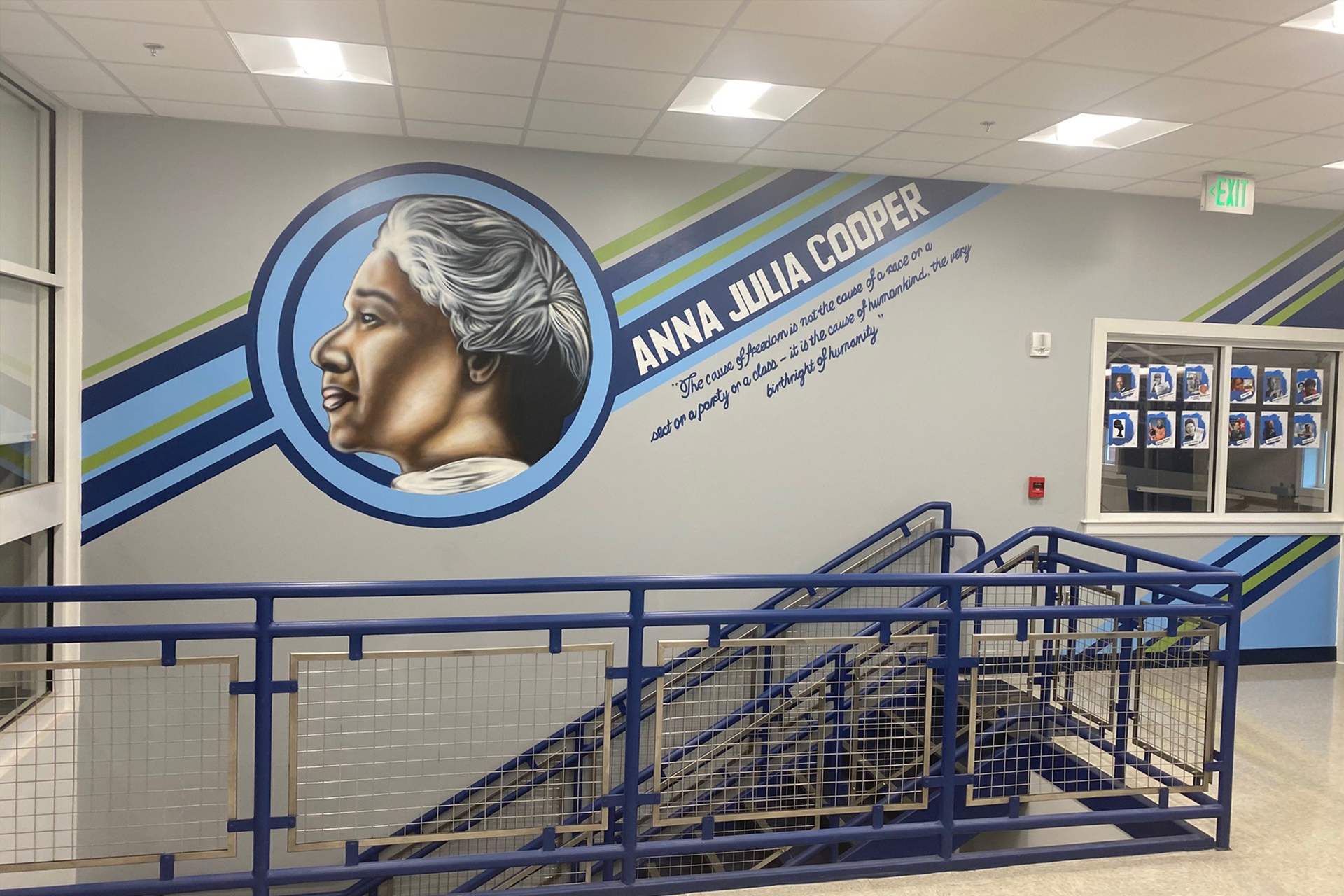 Mural of Anna Julia Cooper with quote on school wall, stairs in foreground. Blue, green, and gray colors.