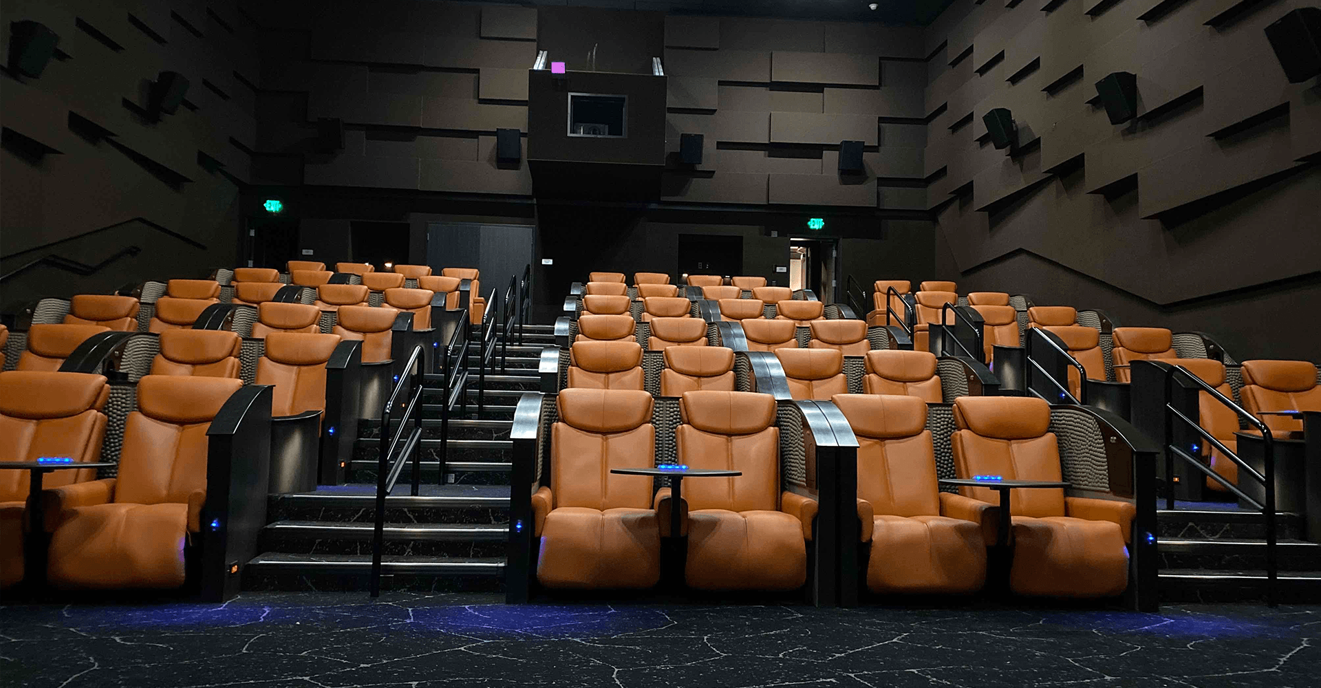 Empty movie theater with orange leather reclining seats and tiered rows.