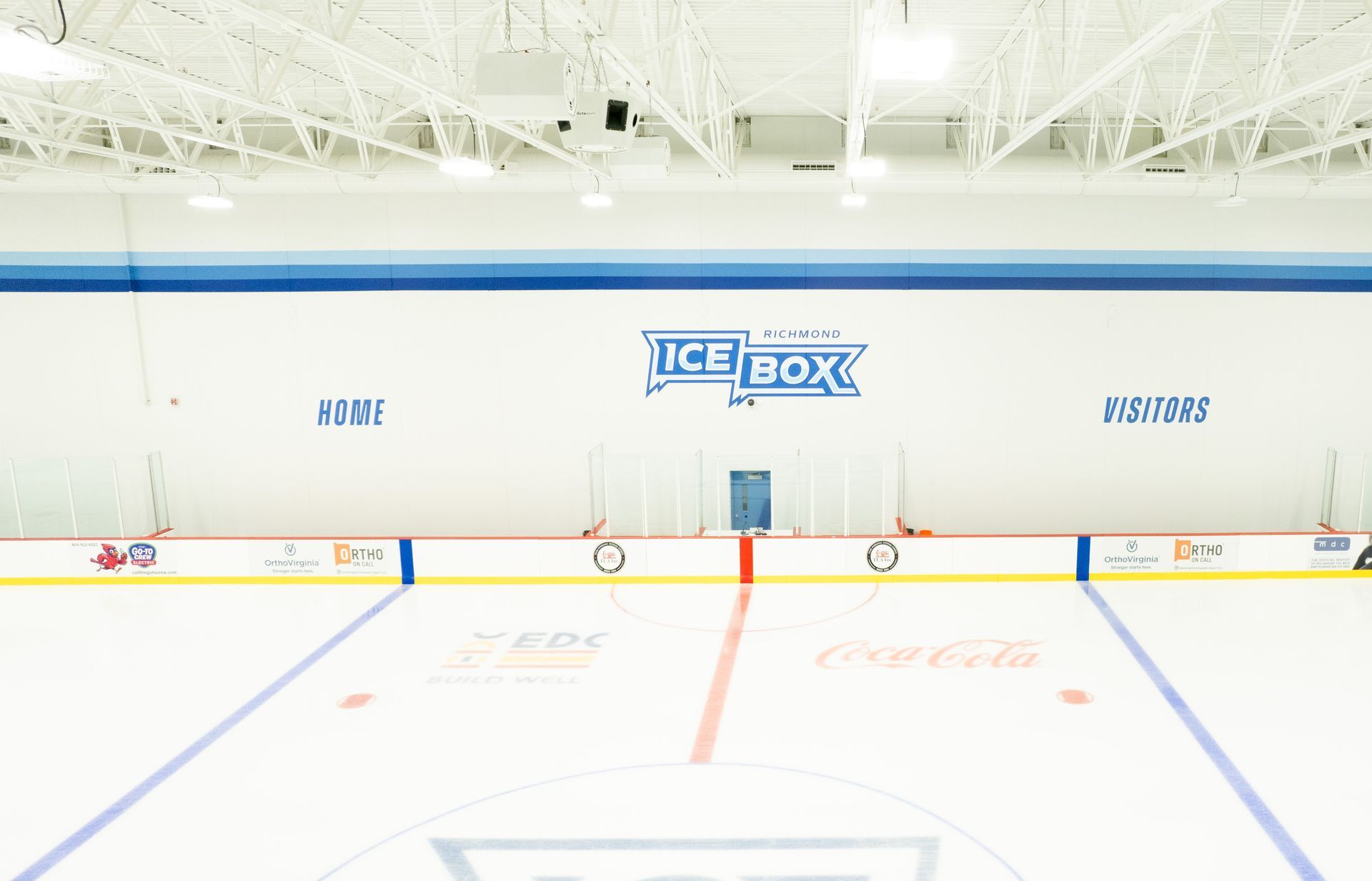 Empty indoor hockey rink with white ice, blue and red lines, and an ICEBOX sign on the far wall