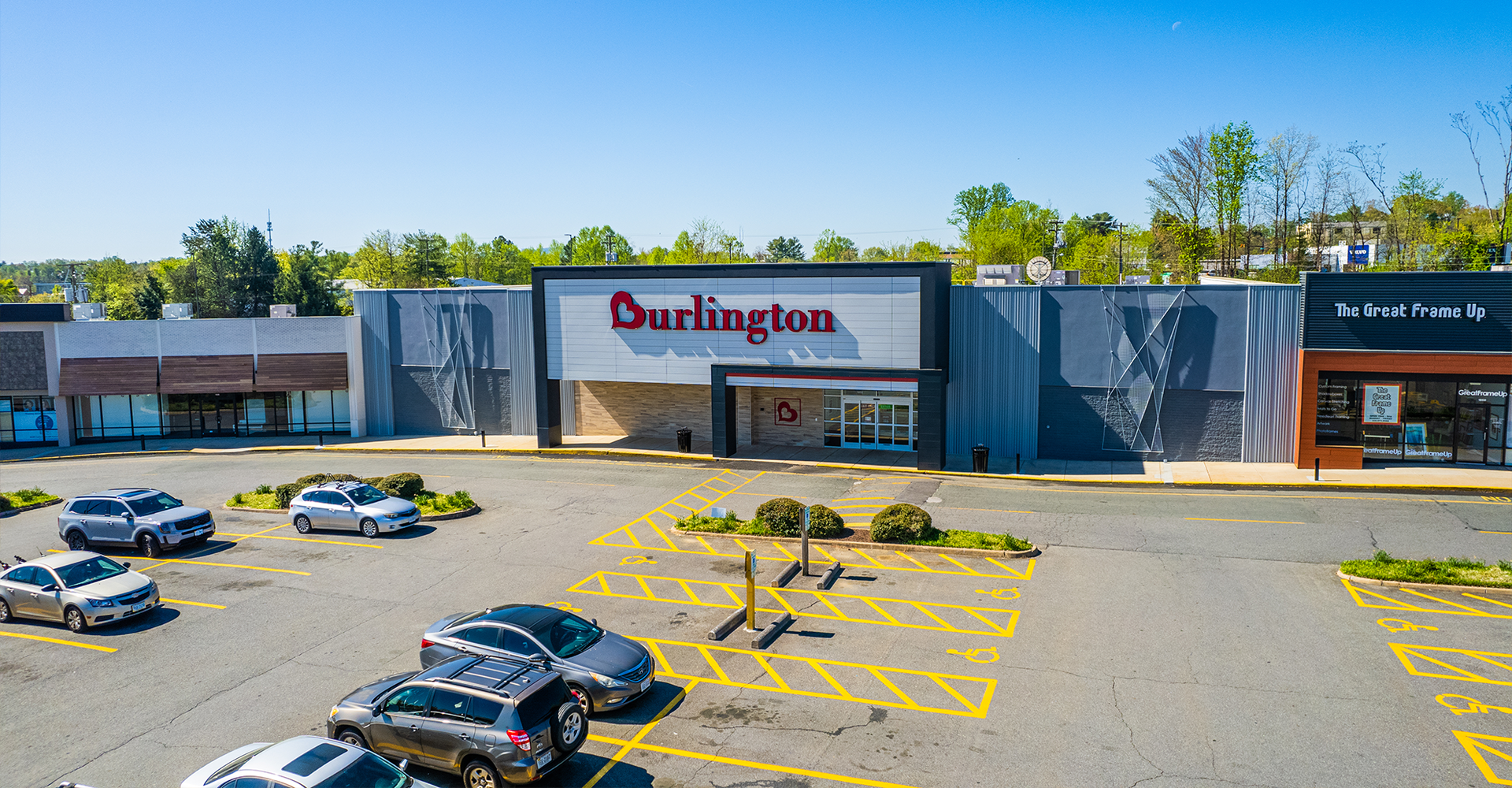 Burlington store exterior with parked cars in a large parking lot on a sunny day.