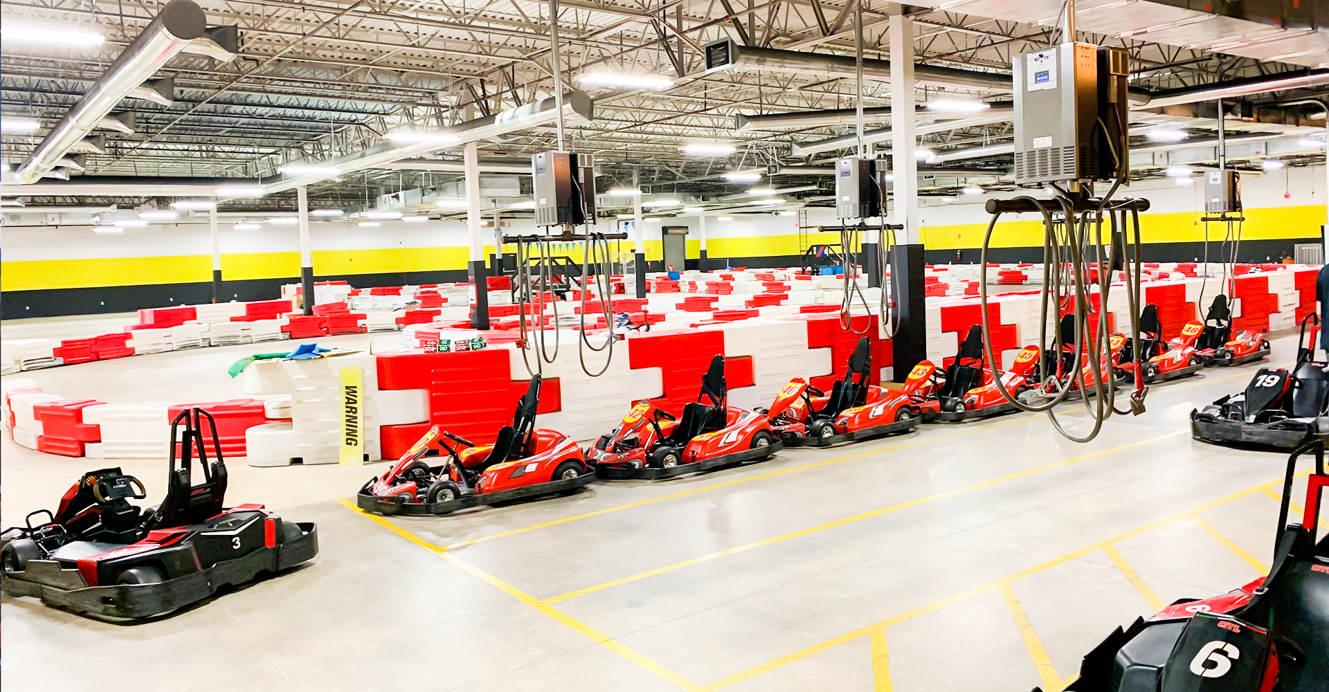 Indoor go-kart track with red and black karts lined up.