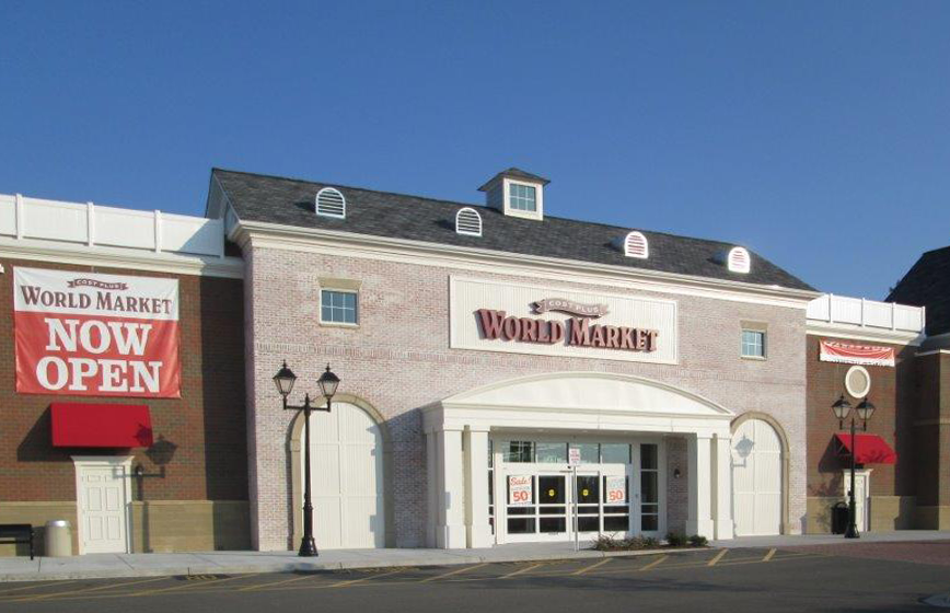 World Market store exterior with red brick, open banner, and arched entrance.