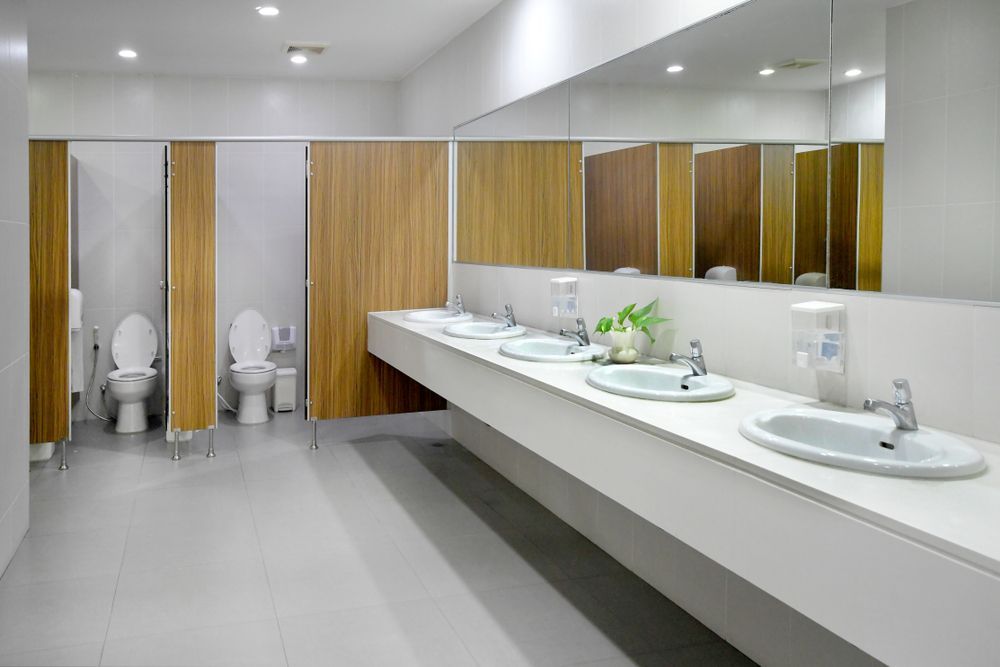 A public restroom with toilets and sinks and a large mirror.