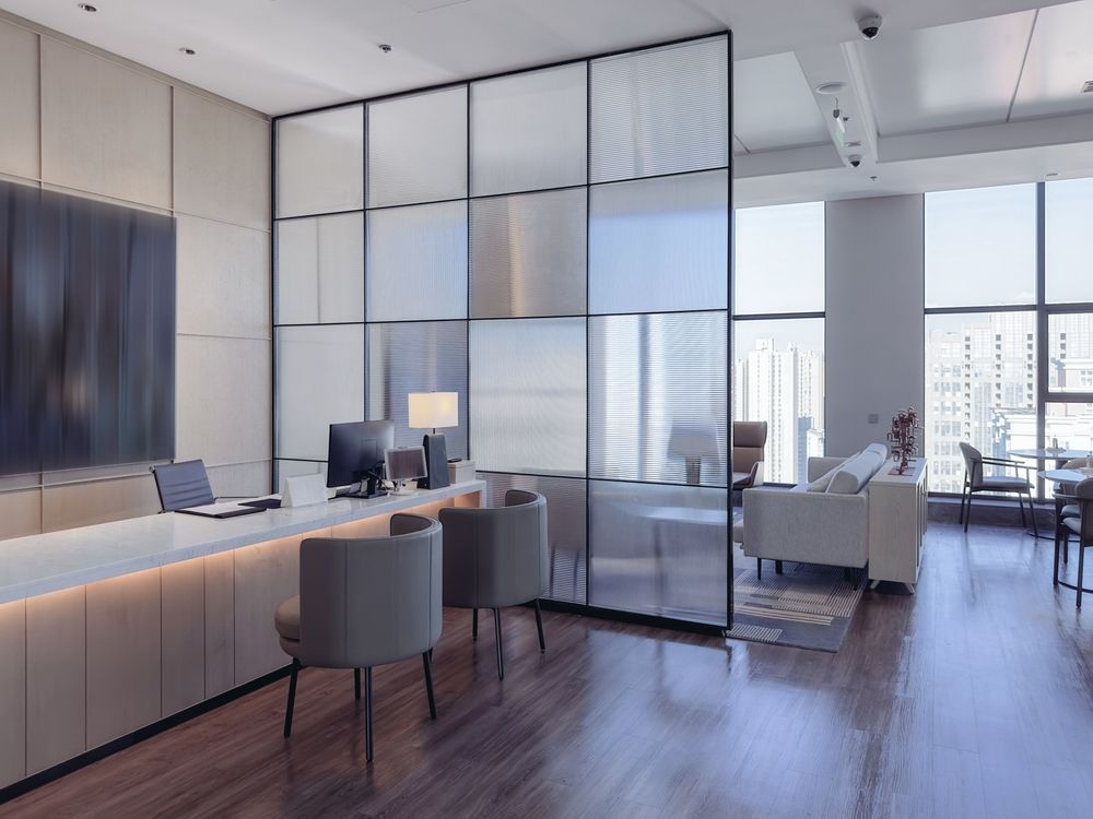 A reception area in an office with a glass divider between the living room and the office.