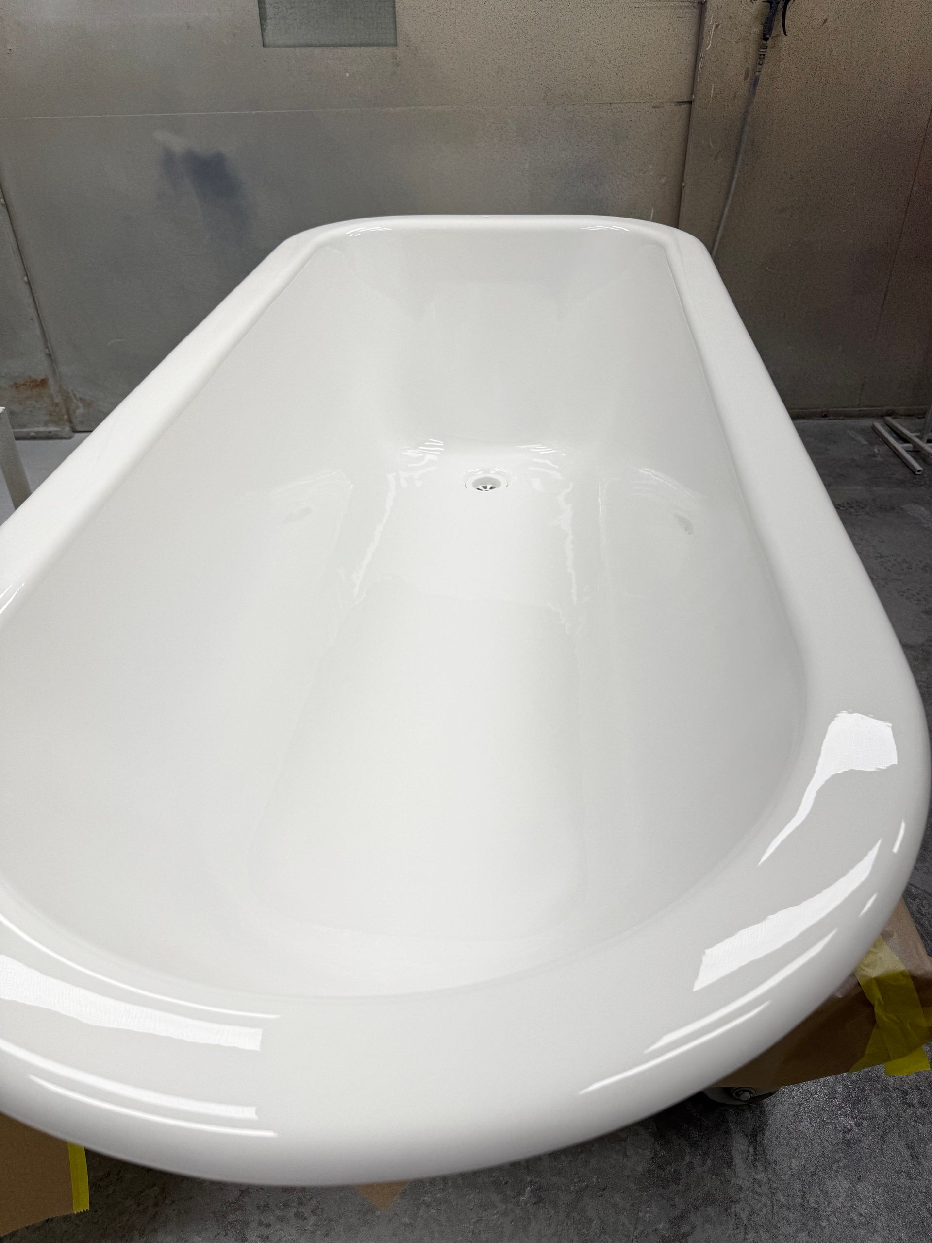 White, glossy clawfoot bathtub, centered in an indoor setting.