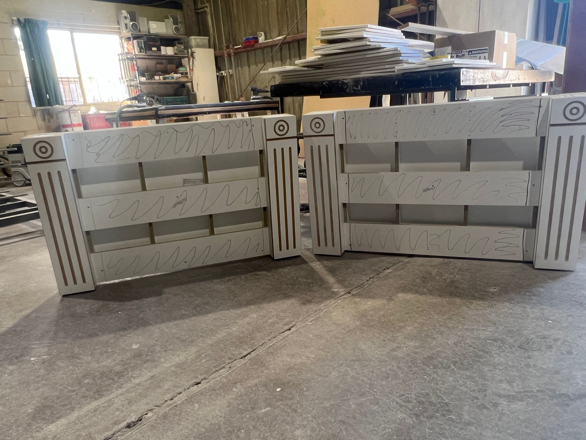 Two light-coloured decorative concrete fence sections, possibly precast, resting on a concrete floor.