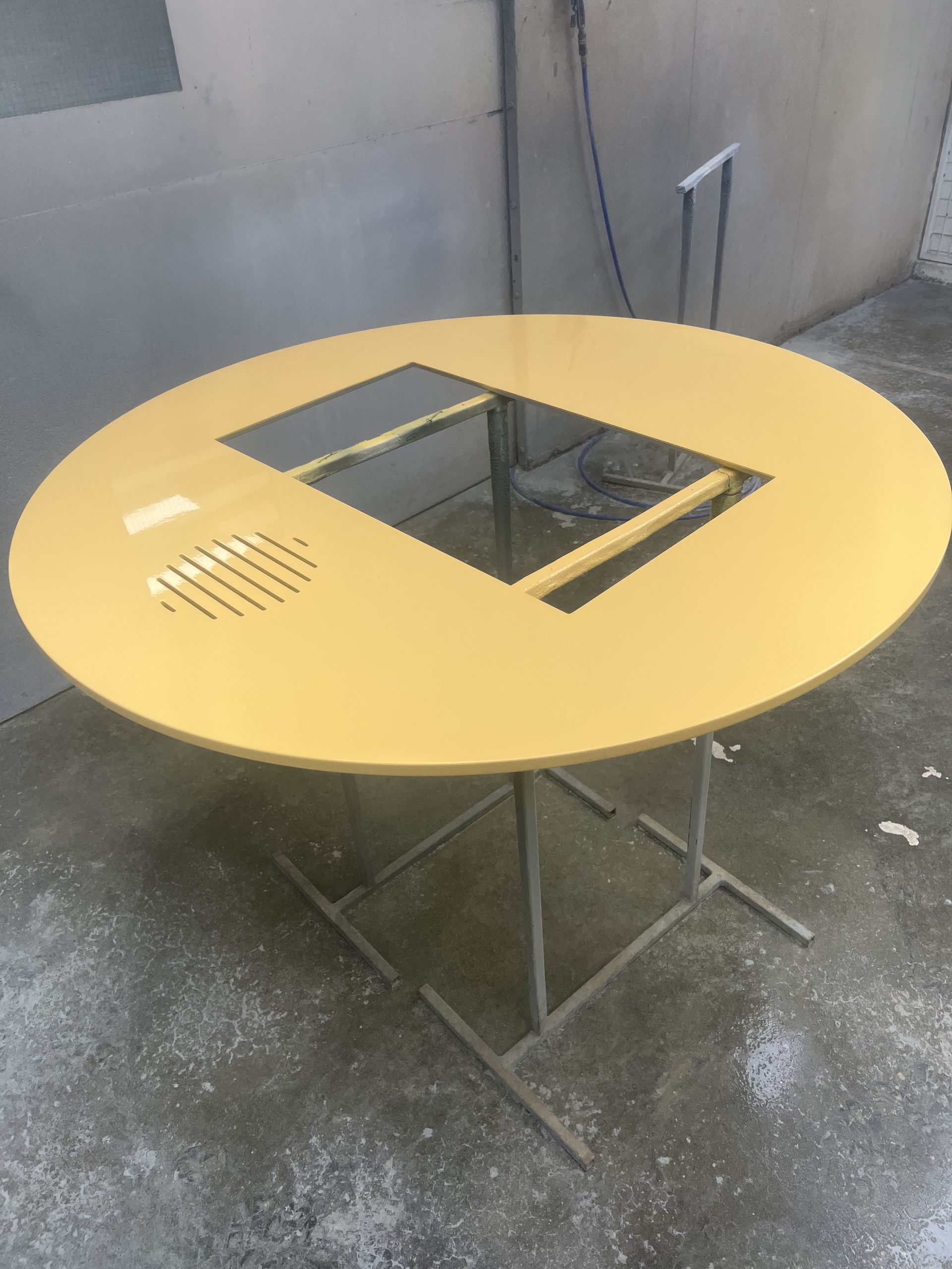 Yellow round table with square cutouts and metal legs.