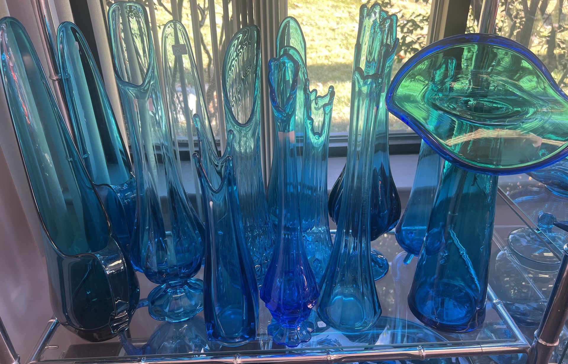 A bunch of blue glass vases on a shelf
