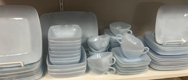 A shelf filled with plates , bowls , and cups.