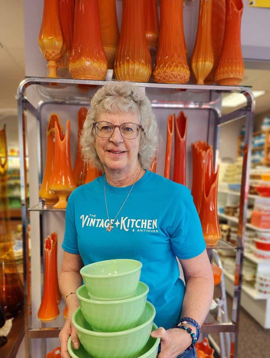 A woman wearing a blue shirt that says vintage kitchen