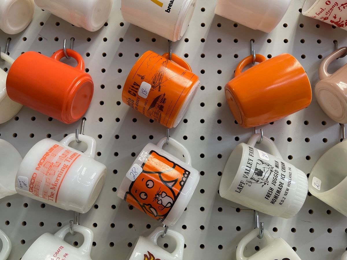 A bunch of coffee mugs are hanging on a wall