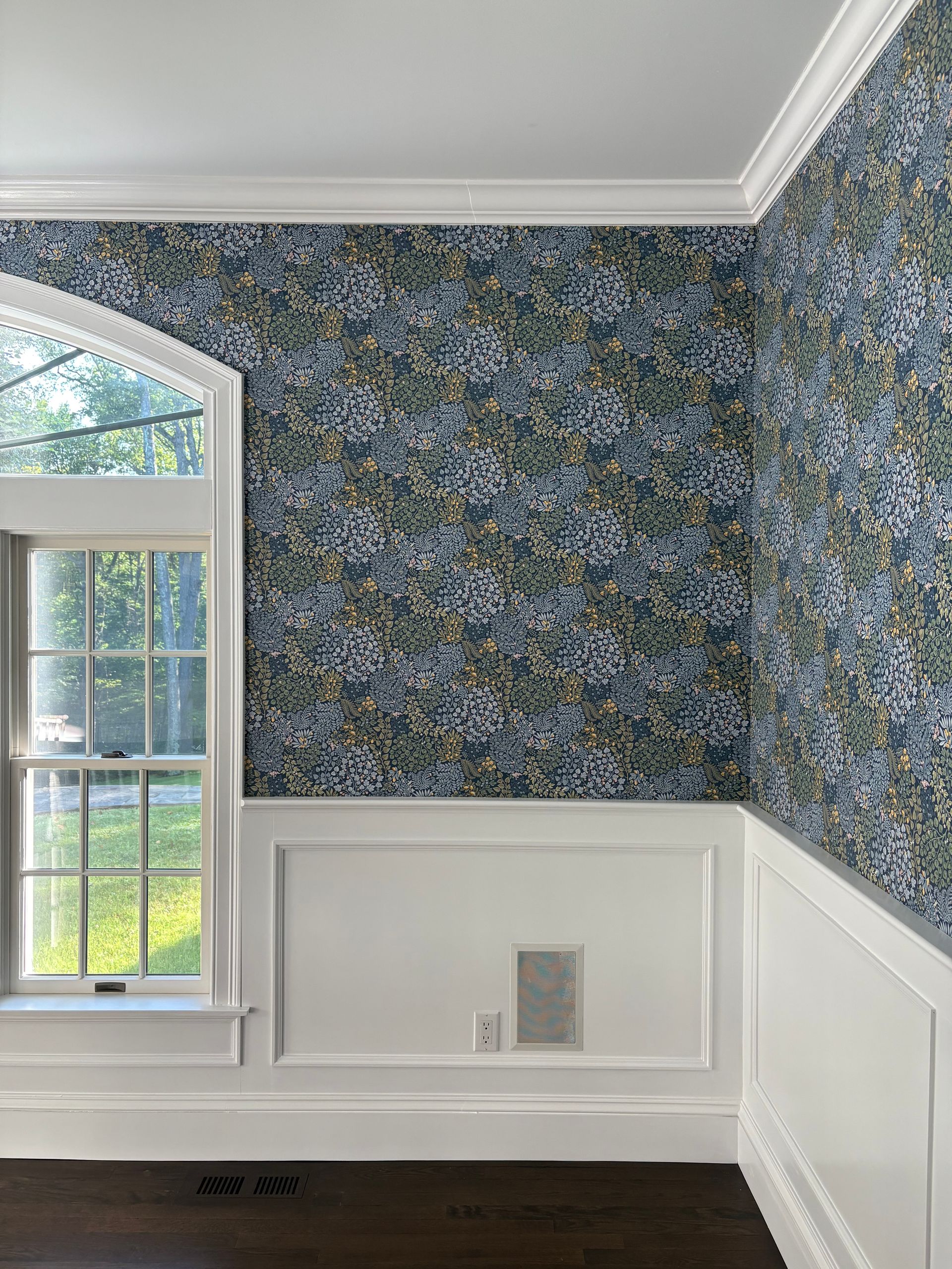 Blue floral wallpaper and white wainscoting.