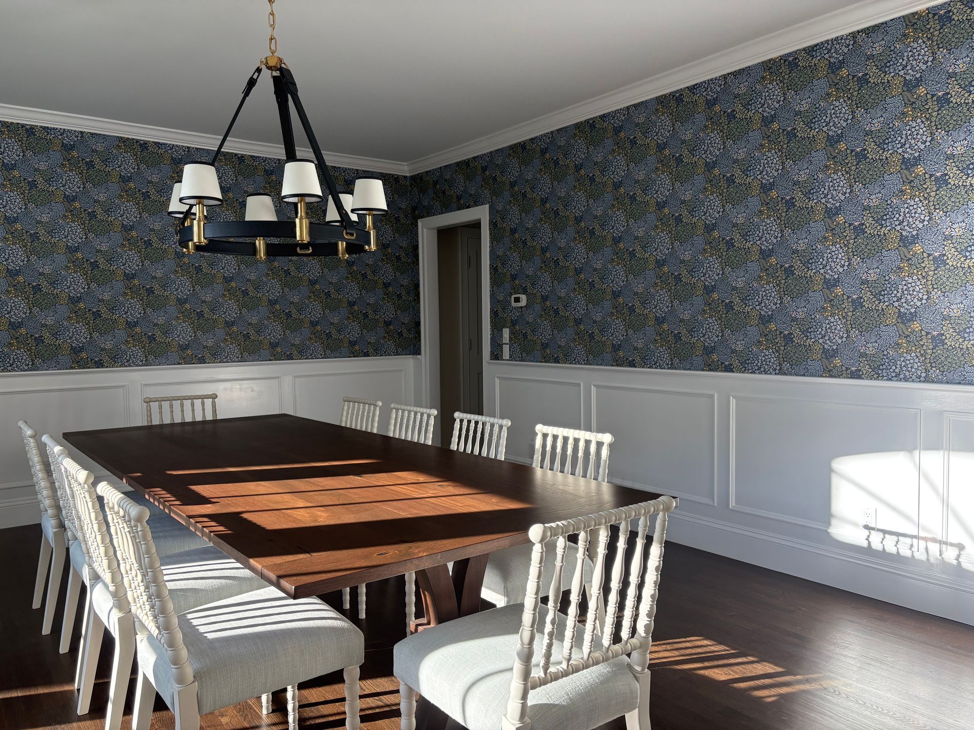 Dining room mural with blue floral wallpaper and white chairs.