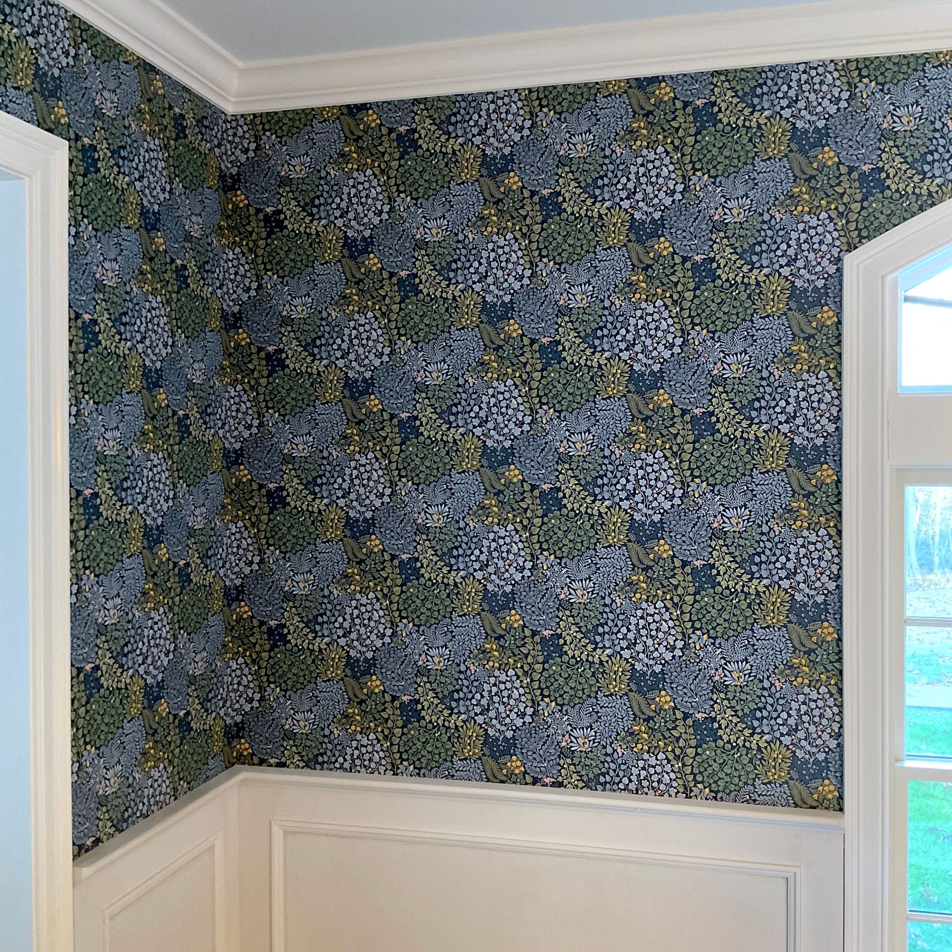 Vibrant floral wallpaper with white wainscoting and crown molding.