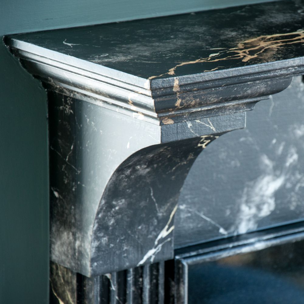 Black marble fireplace with gold veining and carved corbel detail.