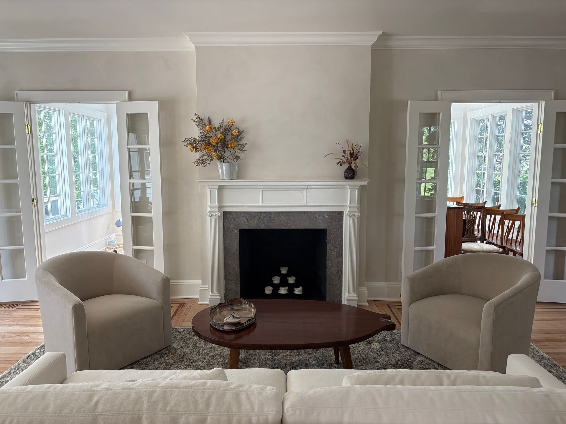 Living room mural with white fireplace, armchairs, and French doors.
