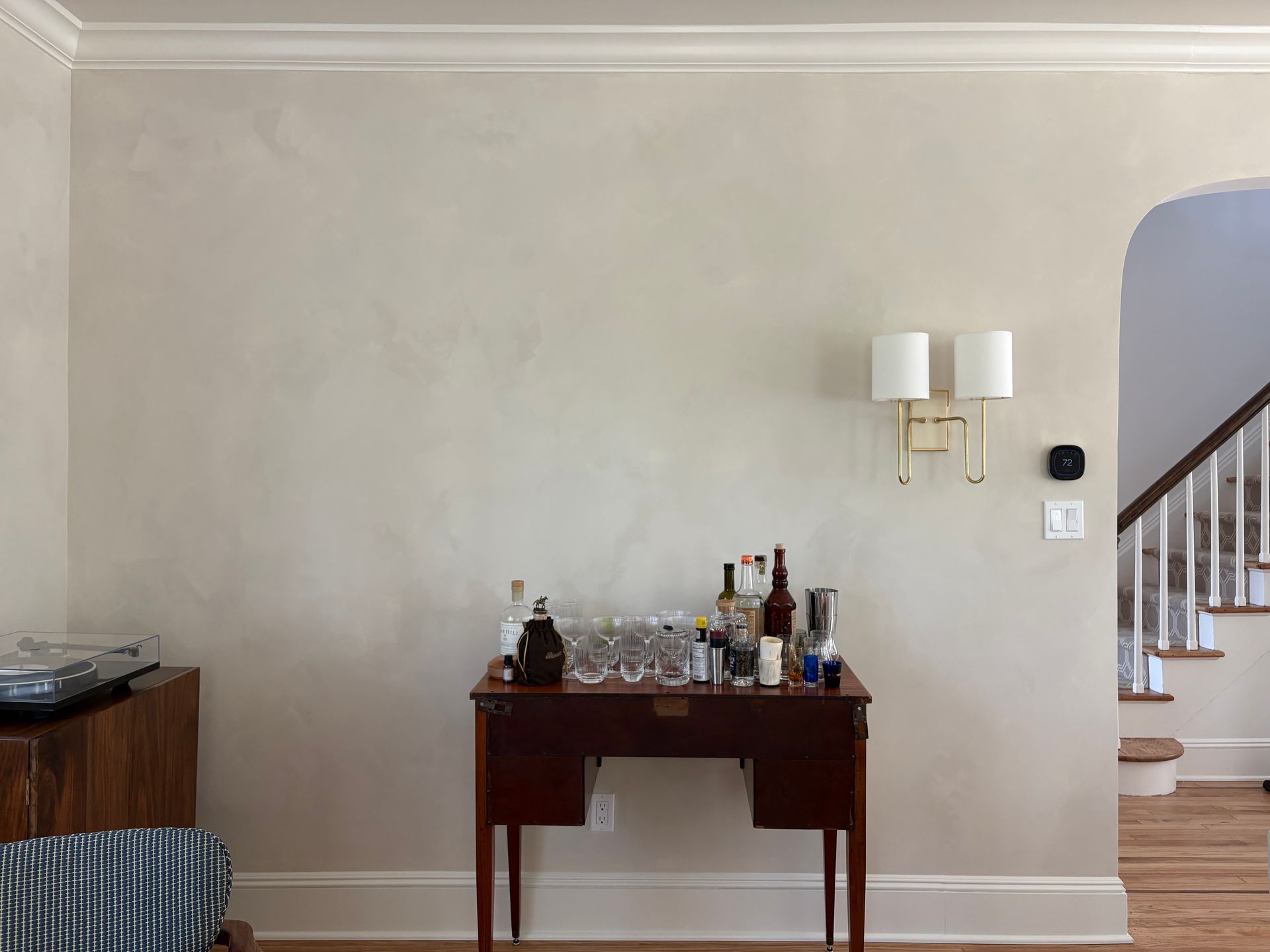Home bar with bottles, glasses, and brass light fixture.
